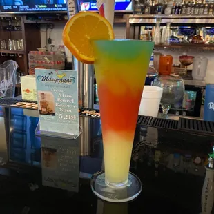 a colorful drink with a slice of orange