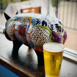 a glass of beer next to a pig statue
