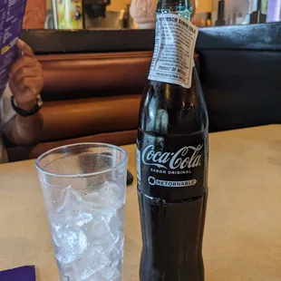 a bottle of coca cola and a glass of water