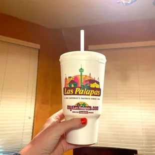 a hand holding a cup with a straw