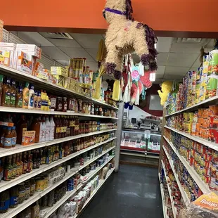 a grocery store aisle with a stuffed animal hanging from the ceiling