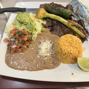 Steak, refried beans, yellow rice and guacamole
