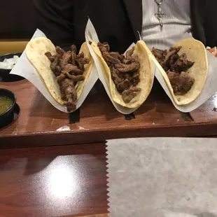 three tacoss on a wooden tray