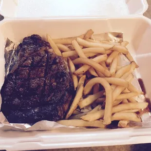 14 oz ribeye with a side of fries in a go box.