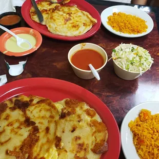 Chicken and cheese Papusas with a side of red rice, and slaw(cabbage) and two different sauces(both plates)