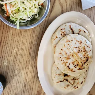 a plate of tortillas and a bowl of coleslaw