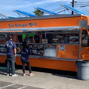 two people standing in front of a food truck