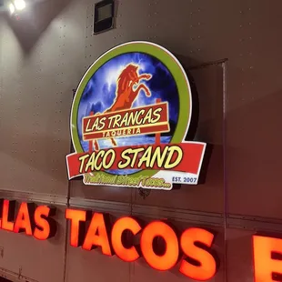 a taco stand with neon signs