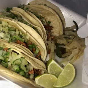 A ready to-go box of 5 al pastor tacos seasoned with onions and cilantro