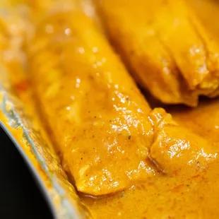 two enchillas in a yellow sauce