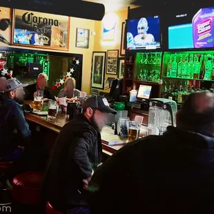 people sitting at a bar watching televisions