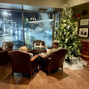 a man and a woman sitting at a table in front of a christmas tree