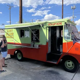 a woman taking a picture of a food truck
