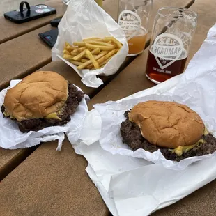two burgers and fries on a picnic table