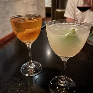 two cocktails on a bar with a man in the background