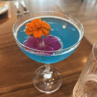a blue cocktail with flowers in it