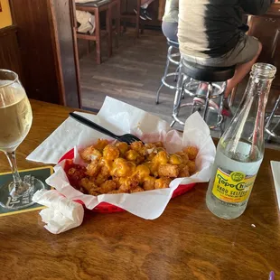 Cheesy taters, white wine and topo chico.