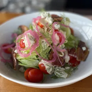 Wedge salad with candied bacon, pickled red onion, Roma tomatoes, and dill, topped with miso blue cheese dressing