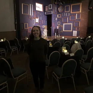a woman standing in a room full of chairs