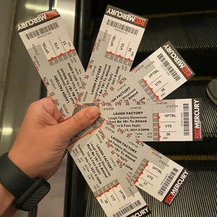 a hand holding a bunch of tickets