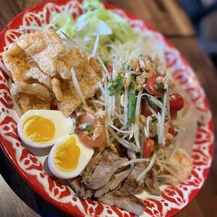 papaya salad with mu yo (pressed pork sausage), deep-fried pork rinds, pickled bamboo shoots, culantro, and boiled eggs