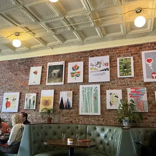 Beautiful interior with exposed brick, tin ceiling, comfortable seating, and modern artwork