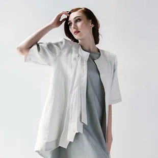 Asymmetry rules this pleat front jacket with a jewel neckline, 3/4 sleeve, pleats at right front and an asymmetric hemline.