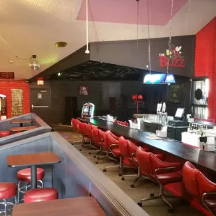 a view of a bar with red chairs