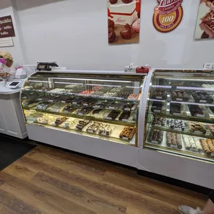 a woman standing in front of a display case of pastries