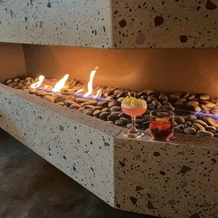 a fire pit with rocks and a glass of wine