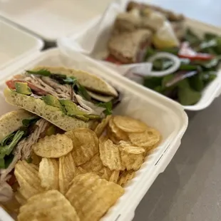 a sandwich and chips in a styrofoam container