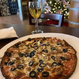 Cauliflower crust pizza with sausage and black olives.