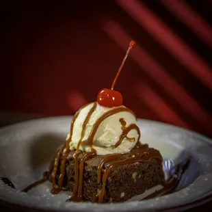 Chocolate brownie with walnuts, topped with salted bourbon caramel sauce and ice cream