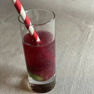 a glass of fruit juice with a striped straw