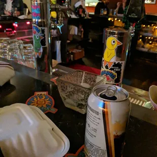 a can of soda and a drink on a bar