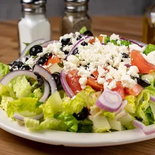 a plate of salad with tomatoes, onions, and feta cheese