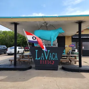 a large blue cow on the roof of a restaurant