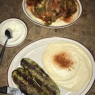 a plate of mashed potatoes, a plate of grilled sausages, and a plate of mashed potatoes