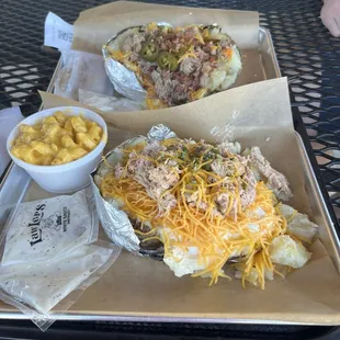 Loaded potato with chicken and a side of mac and cheese (closer). Loaded potato with pulled pork, bacon, and jalapeño (behind)