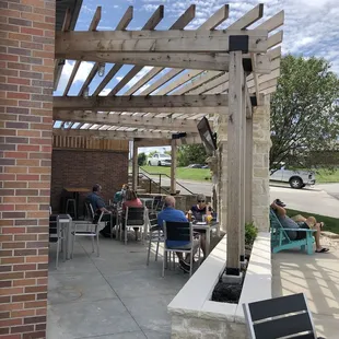 people sitting at tables under a pergol