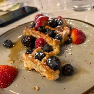 a plate of waffles with berries and powdered sugar