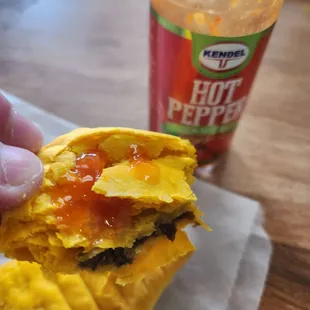 Jamaican patty with some pepper sauce on it.