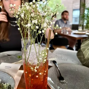 a woman sitting at a table with a vase of flowers