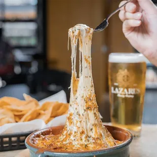 a hand holding a spoon full of cheese dip