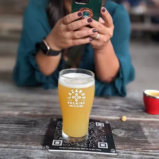 a woman taking a picture of a pint of beer