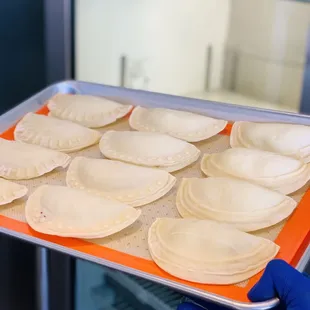 a person holding a tray of empanadas