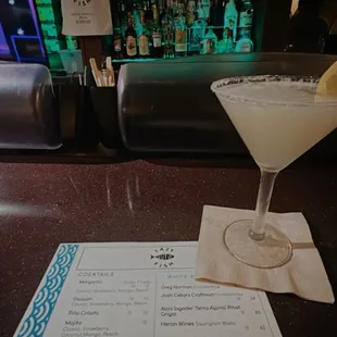 a martini and a menu at a bar