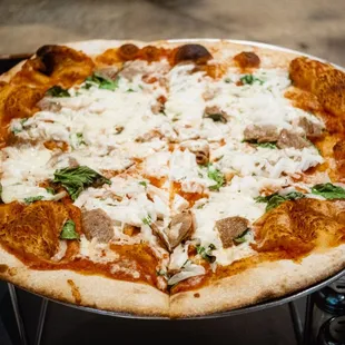 a pizza with meat, cheese, and spinach