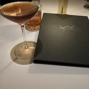 a glass of wine and a book on a table