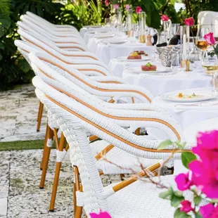 a long table with white tablecloths and pink flowers